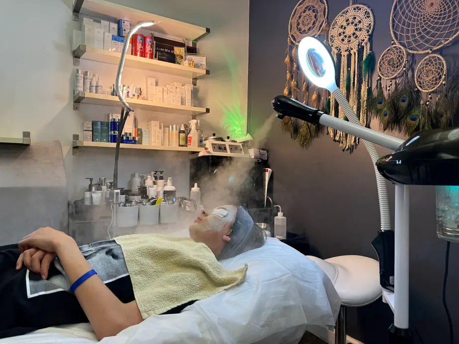 The treatment room at Tulum Spa in Los Angeles, with product shelves, dreamcatcher wall art and low green light