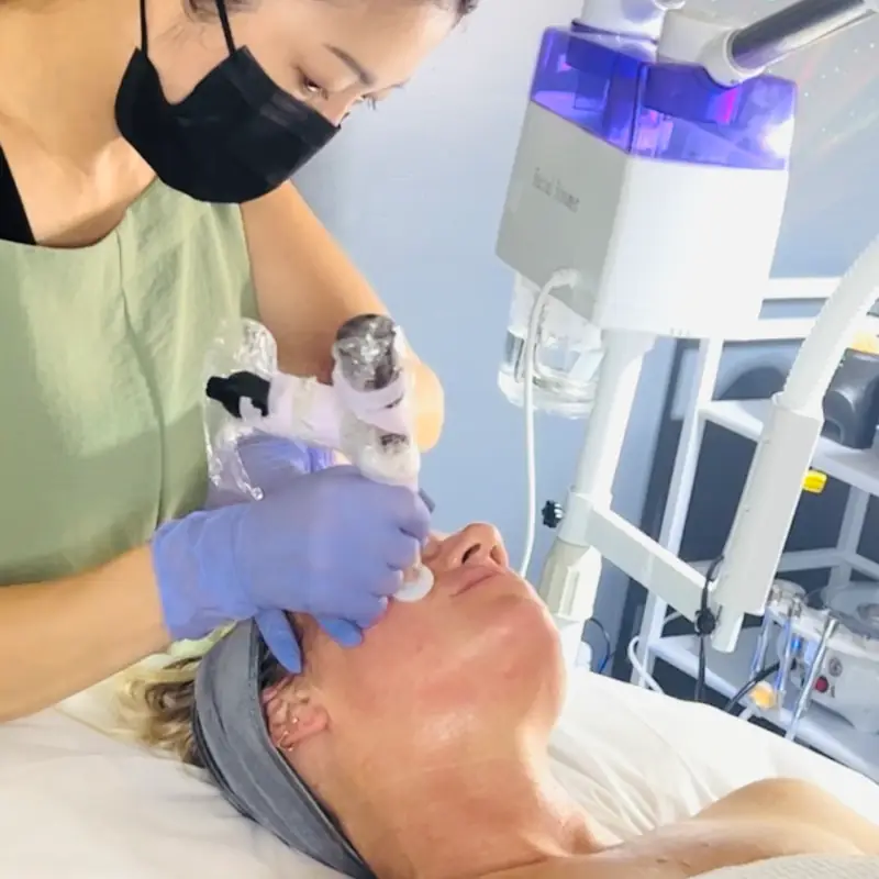 A licensed esthetician in gloves working on a client during a facial at Tulum Spa in Del Rey